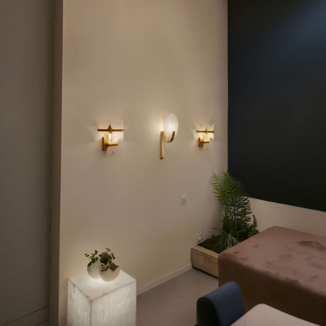 Mica 1 Light Disc Alabaster Wall Light with brushed brass bracket, shown illuminated alongside similar sconces on a wall in a living room setting.