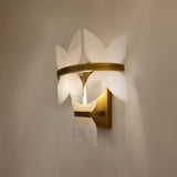 Petraia Floral Alabaster Wall Light in brushed brass, layered stone petals lit warmly, mounted on a plain wall.
