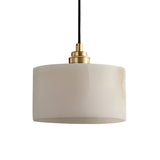 The Brinex 1 Light Alabaster Single Pendant Light features a cylindrical, soft white opaque shade with a brushed brass fixture, suspended by a black cord against a plain white background.