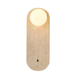 The Arvella 1 Light Travertine & Glass Wall Light in light beige features an elongated, rounded travertine base with a circular white glass top, creating a minimalist look reminiscent of the moon over textured stone.