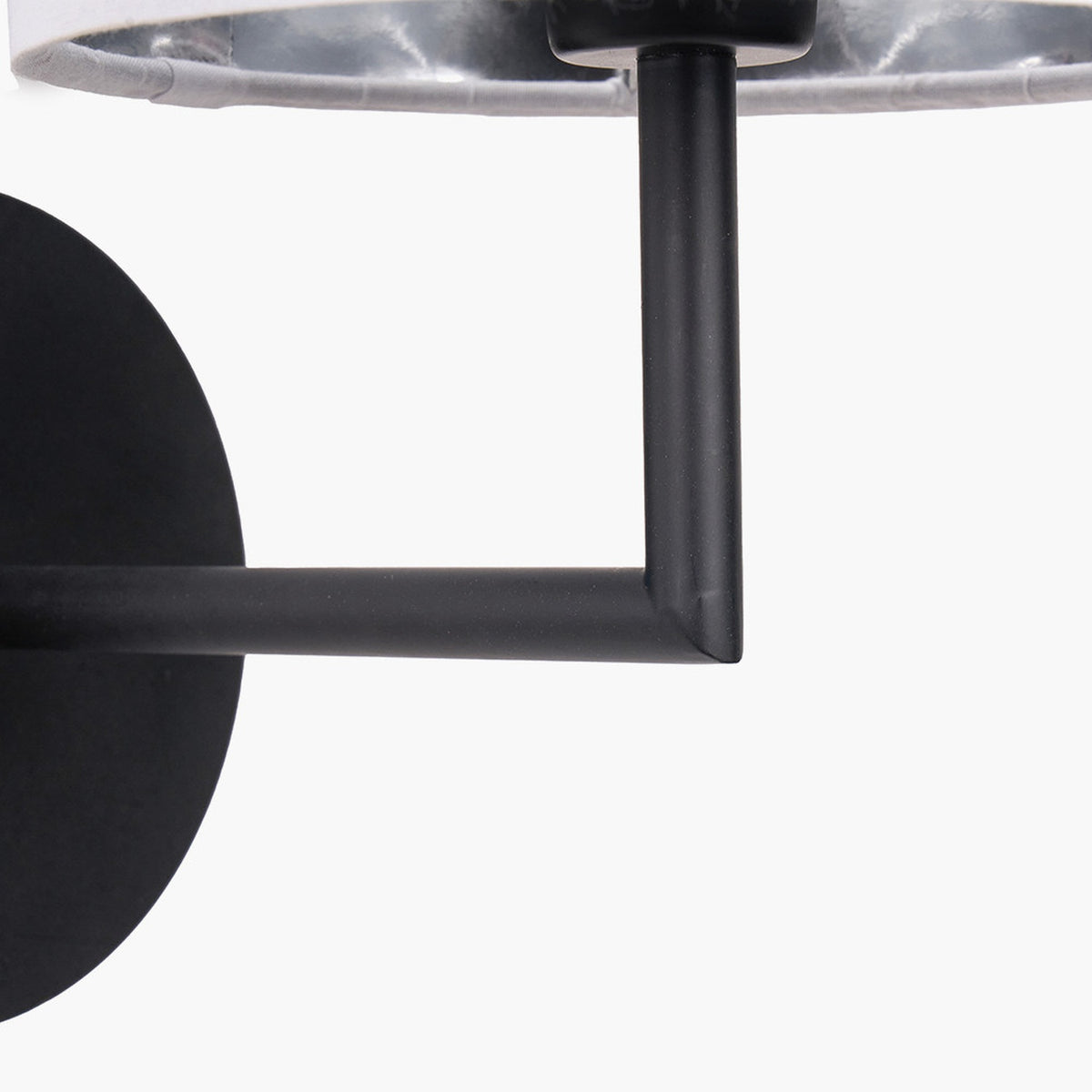 Close-up of the Elin Matt Black & Ivory Wall Light's angular metal arm and round wall plate, with ivory fabric shade edge visible above.