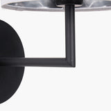 Close-up of the Elin Matt Black & Ivory Wall Light's angular metal arm and round wall plate, with ivory fabric shade edge visible above.