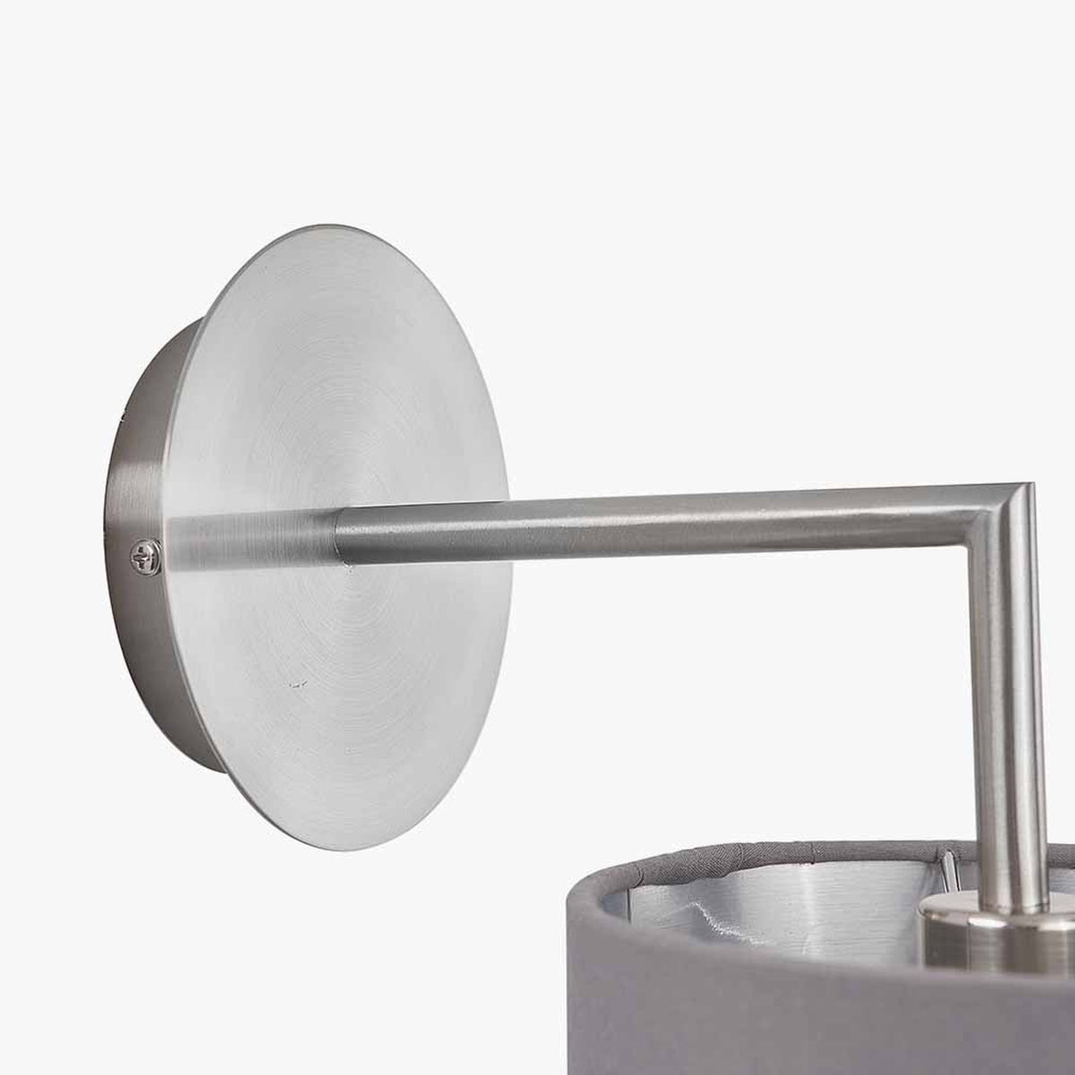 Close-up of the Elin wall light in brushed silver, showing the round wall plate, straight arm, and angled fitting above a grey fabric shade on a plain white background.