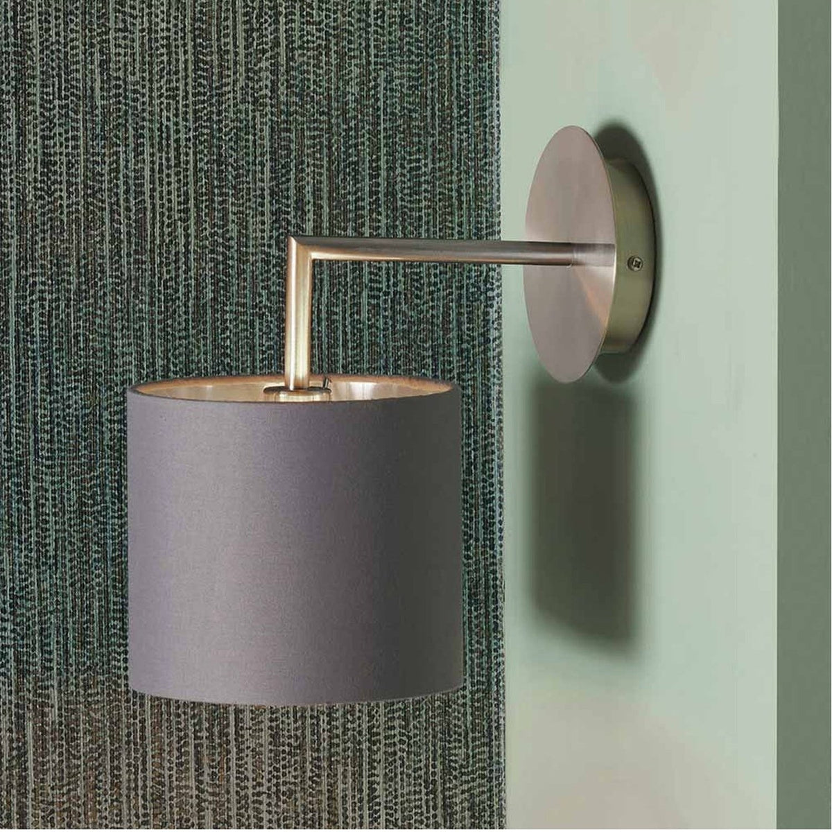 Elin Brushed Silver & Steel Grey Wall Light, 26cm, with angled metal arm and grey fabric drum shade, mounted on a textured green fabric-covered wall.