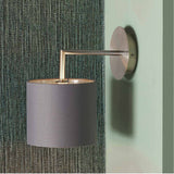 Elin Brushed Silver & Steel Grey Wall Light, 26cm, with angled metal arm and grey fabric drum shade, mounted on a textured green fabric-covered wall.