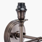 Close-up of the Piero double wall light's antique bronze fitting, showing the bulb holder, decorative round backplate, and dual arm mounts on a plain white background.