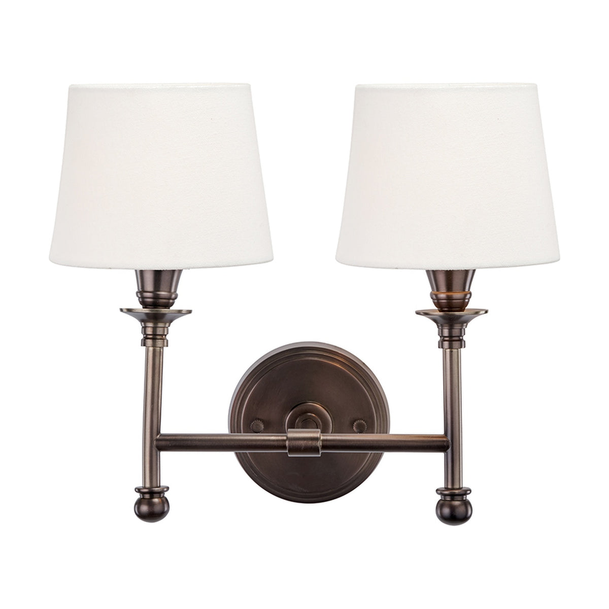 Piero Antique Bronze Double Wall Light with two tapered white fabric shades on curved metal arms, mounted on a round bronze backplate, shown on a plain white background.