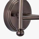 Close-up of the Piero Double Wall Light in antique bronze, showing the round metal backplate, dimmer knob, straight arm, and ball-tipped finial against a plain white background.