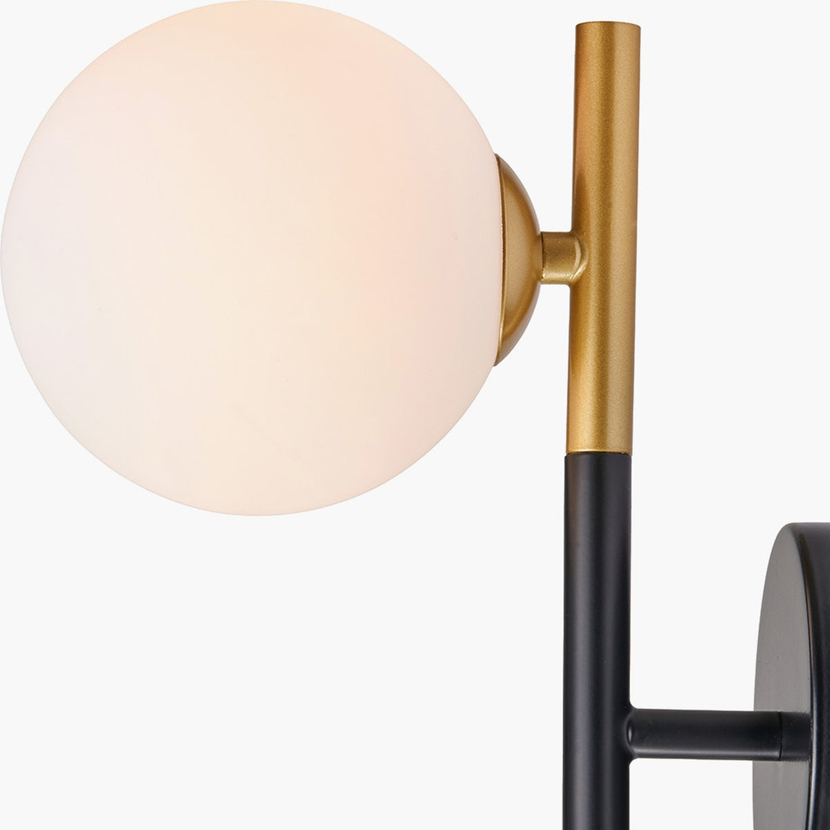 Close-up of the Wanda White Orb & Black Metal Wall Light showing a white glass globe shade, brass-tone stem, and black metal backplate on a plain background.
