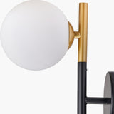 Close-up of the Wanda White Orb & Black Metal Wall Light, showing a white glass globe shade joined by a brass fitting to a black and gold metal stem on a plain background.
