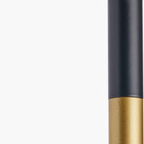 Close-up of the Wanda wall light's matte black metal stem transitioning to a brushed brass-toned lower section, shown against a plain white background.