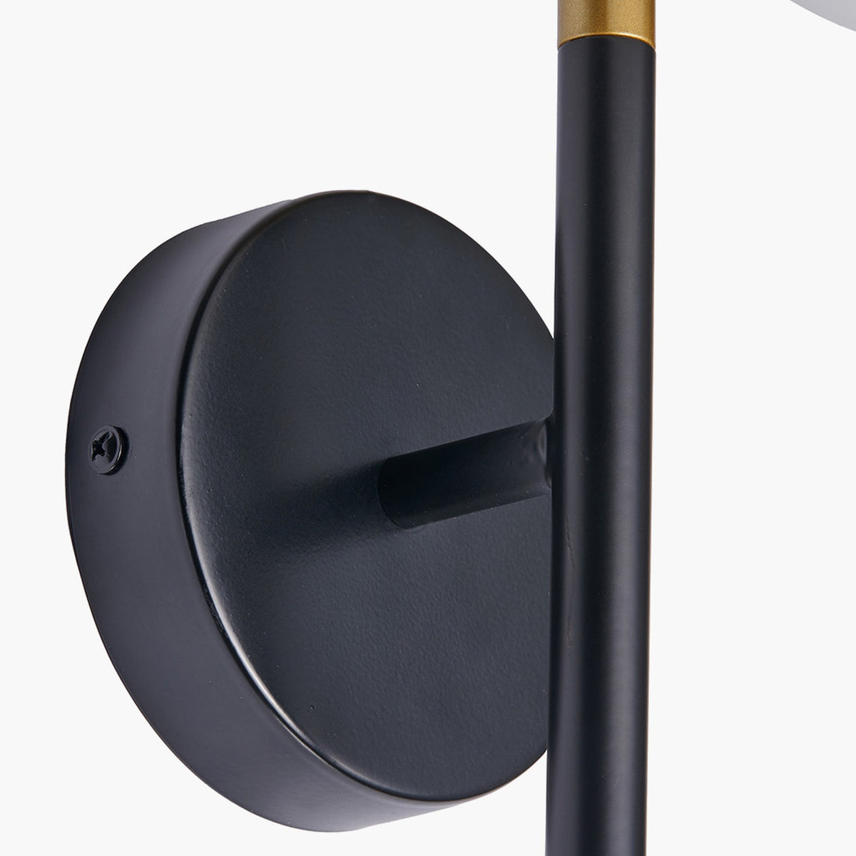 Close-up of the Wanda wall light's matte black round wall mount and rod, with visible screw fixing and brass-accented black stem, against a plain white background.