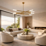 A modern living room with white sofas, round chairs, a large round coffee table, built-in fireplace, floor-to-ceiling ocean-view windows, and an Aurelian LED Layered Arms Alabaster Chandelier in brushed brass & soft white overhead.