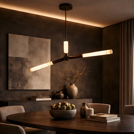 A modern dining room with a round table, neutral chairs, and the Aurelian LED Triple Arm Alabaster Pendant Light in Matte Black & Soft White. Warm lighting highlights textured gray walls, abstract art, and decorative vases on a sideboard.