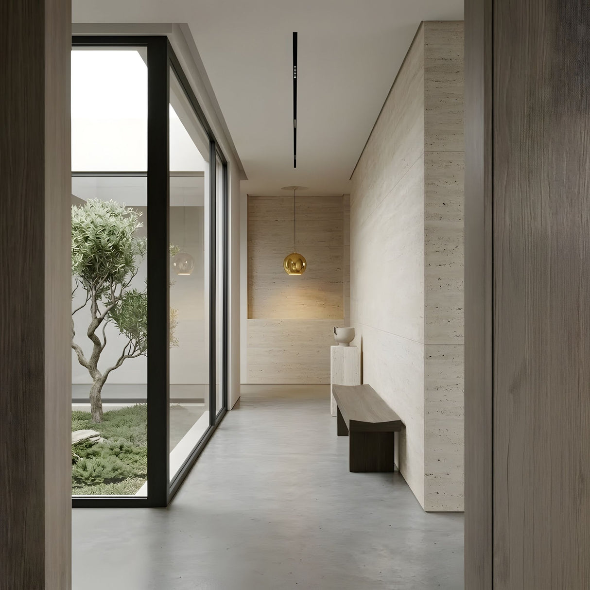 Minimalist hallway with light wood walls and concrete floor, featuring a wooden bench, white sculpture, and the Grand Ball Glass Pendant 25cm – Gold. A large window reveals a green courtyard with a tree and lush plants.