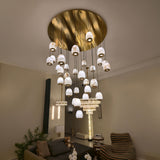 Aurevia 31-Light LED Alabaster Chandelier with brushed brass round canopy and cascading pebble-shaped shades, shown suspended in a living room setting.