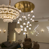 Aurevia 31-light LED alabaster chandelier with brushed brass canopy and cables, pebble-shaped drops shown suspended in a living room setting.
