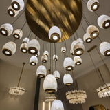 Aurevia 31-light LED alabaster chandelier in brushed brass with hand-carved alabaster drops on a circular canopy, shown lit with warm-white light.