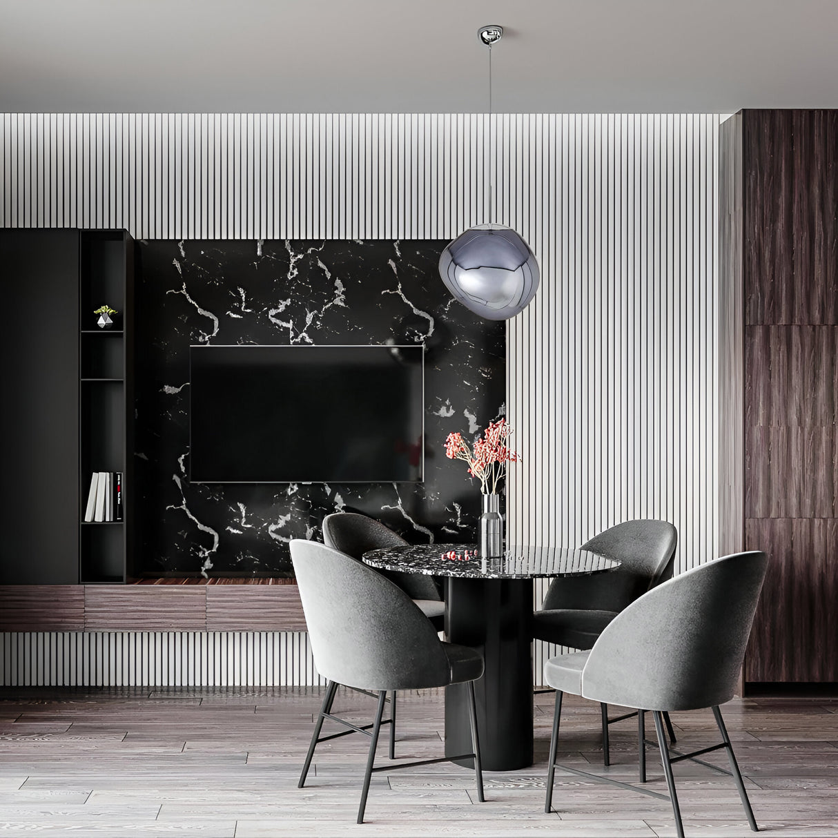 A modern dining area with a round black marble table, four gray upholstered chairs, a black marble TV wall, and the Lava Small LED Pendant Light - Smoked, featuring a sculptural smoked acrylic shade against white panels and dark wood accents.