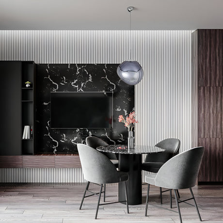 A modern dining area with a round black marble table, four gray upholstered chairs, a black marble TV wall, and the Lava Small LED Pendant Light - Smoked, featuring a sculptural smoked acrylic shade against white panels and dark wood accents.