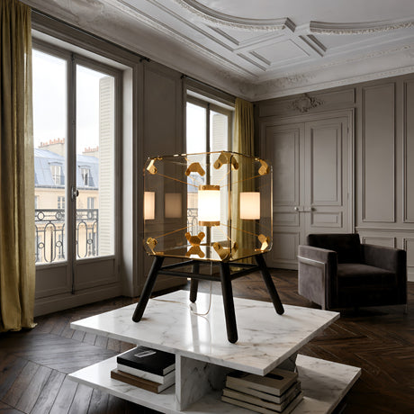 The Qbic LED Small Floor Light - Clear adds a modern touch as it sits on a marble coffee table in an elegant room with large windows, yellow curtains, wooden floors, and gray paneled walls.
