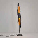 The Stealth 6 Light Floor Lamp - Brass & Black features a tall, modern design with brass and black panels on a round black base—an eye-catching sculptural piece perfect for contemporary spaces.