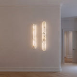 Arvella Small Alabaster Column Wall Light in soft white, paired vertical alabaster cylinders glowing warm white on a hallway wall.