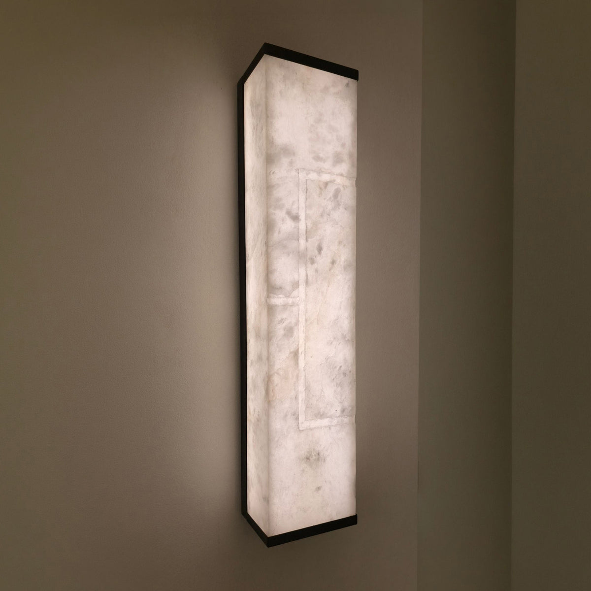 Eryndor LED Alabaster Wall Light in matt black and soft white, tall rectangular panel with recessed lit channel, mounted on a wall and glowing warm white.