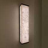 Eryndor LED Alabaster Wall Light in matt black and soft white, tall rectangular panel with recessed lit channel, mounted on a wall and glowing warm white.