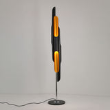 Niori Stealth 6 Light Floor Lamp with staggered matt black tubular shades and brushed brass interiors on a slim chrome stem and round black base.
