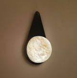 Lunara 1 Light Teardrop Wall Light with matt black backplate and round alabaster disc, mounted on a plain neutral wall.