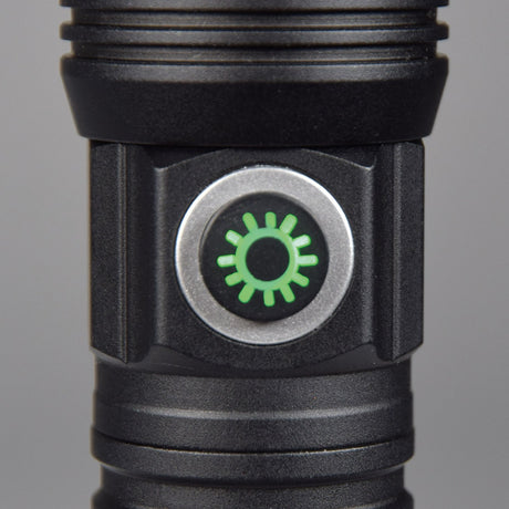 Close-up of the AVSL Mercury Rechargeable LED Torch power button with green illuminated sun icon on a silver ring, set into the black metal body.