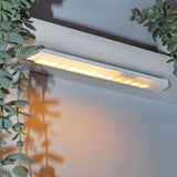 LYYT 36 LED motion sensing light bar by AVSL, mounted under a shelf with warm illumination on a white wall beside trailing eucalyptus foliage.