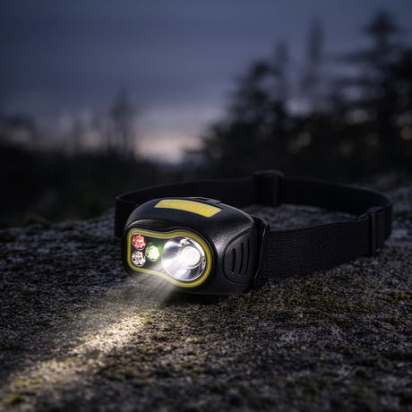 Mercury 3W XPE head torch with black and yellow casing, red, green and white LEDs, elastic strap, worn on rock outdoors with beam lit.