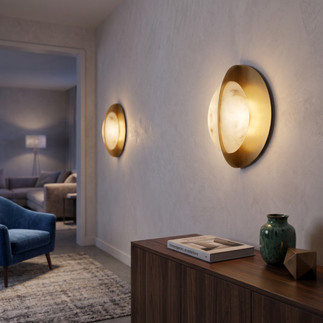 Niori Althia LED alabaster wall lights in brushed brass, mounted in a hallway above a walnut sideboard with a green vase and architecture book.