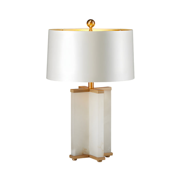 The Table 1 Light Column Alabaster Table Lamp in brushed brass and soft white features a rectangular alabaster base, gold accents, and a white drum shade topped with a gold finial for an elegant touch.