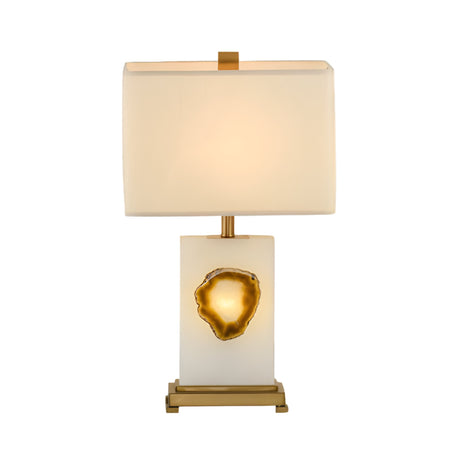 The Selune 1 Light Sculpted Core Alabaster Table Lamp features a modern alabaster base with a brushed brass geode-like accent, gold detailing, and a soft white rectangular shade.