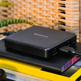 Mercury 65W GaN charger in matt black with two USB-C and two USB-A ports labelled on the side, cable connected, resting on a notebook.