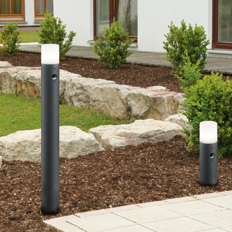 Hoosic 80cm PIR lamp post in anthracite, a slim aluminium bollard light with white cylindrical diffuser and motion sensor, shown installed in a garden path setting.