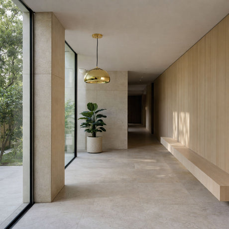 A minimalist hallway with large windows, light stone floors, a built-in wooden bench, a potted plant, and modern decor. The space is bright and modern, featuring the Gulf Glass Pendant Light - Gold as a stylish centerpiece.