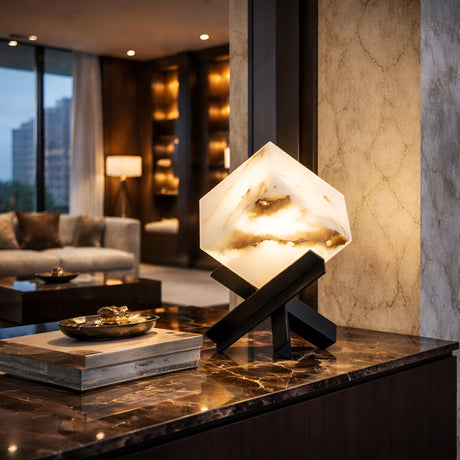 The Kalythra 1 Light Faceted Alabaster Table Lamp in soft white and matte black sits on a polished marble console in a modern, warmly lit living room with large windows and elegant décor.