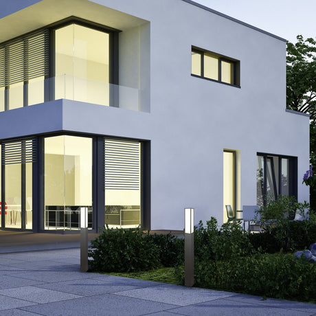 Fuerte LED bar outdoor lamp posts in anthracite illuminate a modern house entrance path, showing their slim square profile and frosted glowing heads at night.