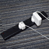 AVSL Mercury 6 Gang 13A trailing socket in black with two white Apple plug adapters connected, shown on a striped grey carpet floor.
