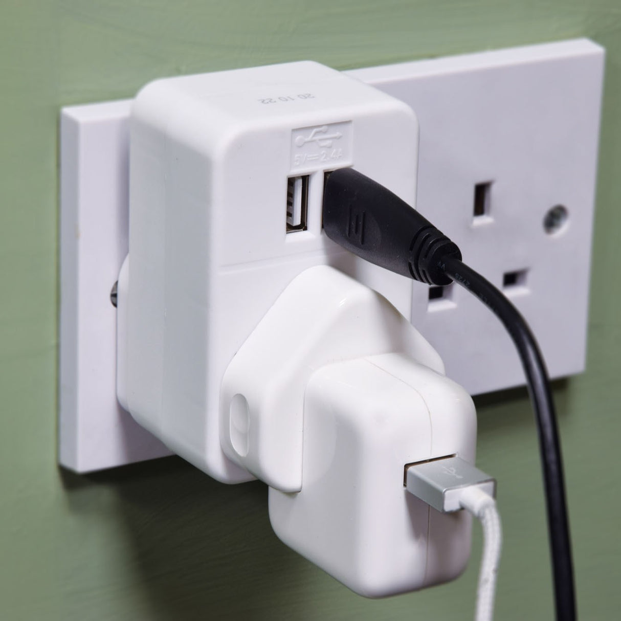 Mercury 1 Way Mains Adaptor by AVSL plugged into a UK wall socket, with a USB-A cable and a white plug charger connected through it.