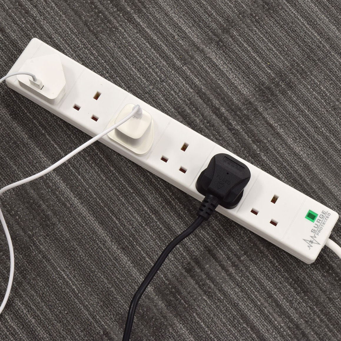 AVSL Mercury 6 gang extension lead in white with surge protection, three UK plugs connected and green neon indicator, shown on grey carpet.