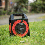 Mercury 15m 4-gang cable reel in red and black with orange cable and four UK 13A sockets, shown standing on grass outdoors.