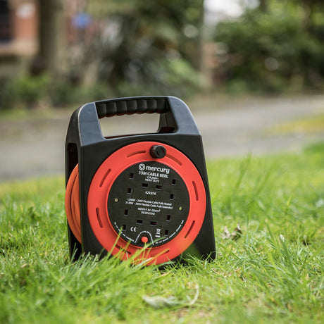 Mercury 15m 4-gang cable reel in red and black with orange cable and four UK 13A sockets, shown standing on grass outdoors.