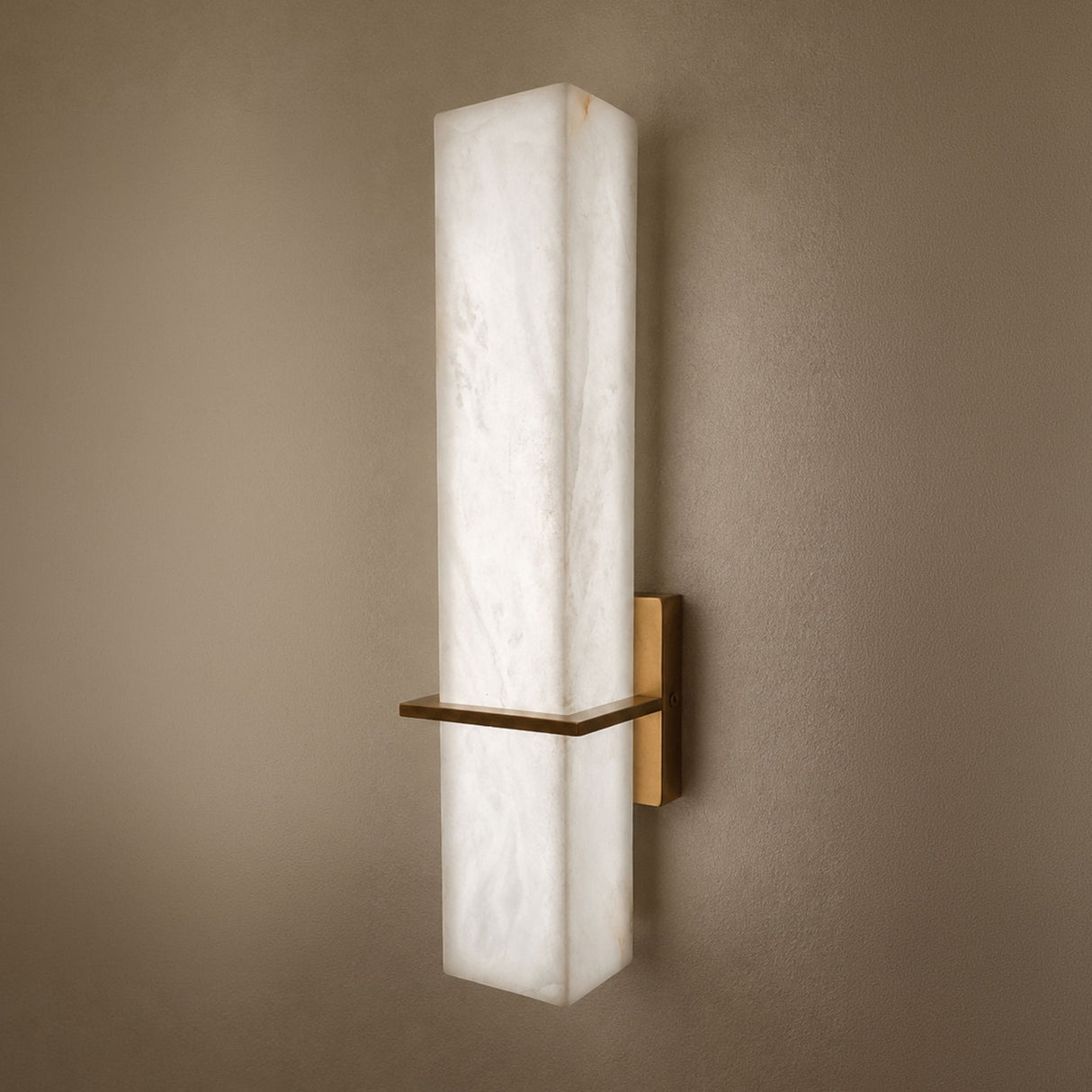 Aurevon LED Alabaster Vertical Panel Wall Light in brushed brass, showing an elongated rectangular alabaster panel glowing warm-white on a taupe wall.