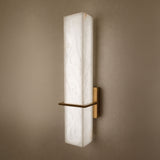 Aurevon LED Alabaster Vertical Panel Wall Light in brushed brass, showing an elongated rectangular alabaster panel glowing warm-white on a taupe wall.