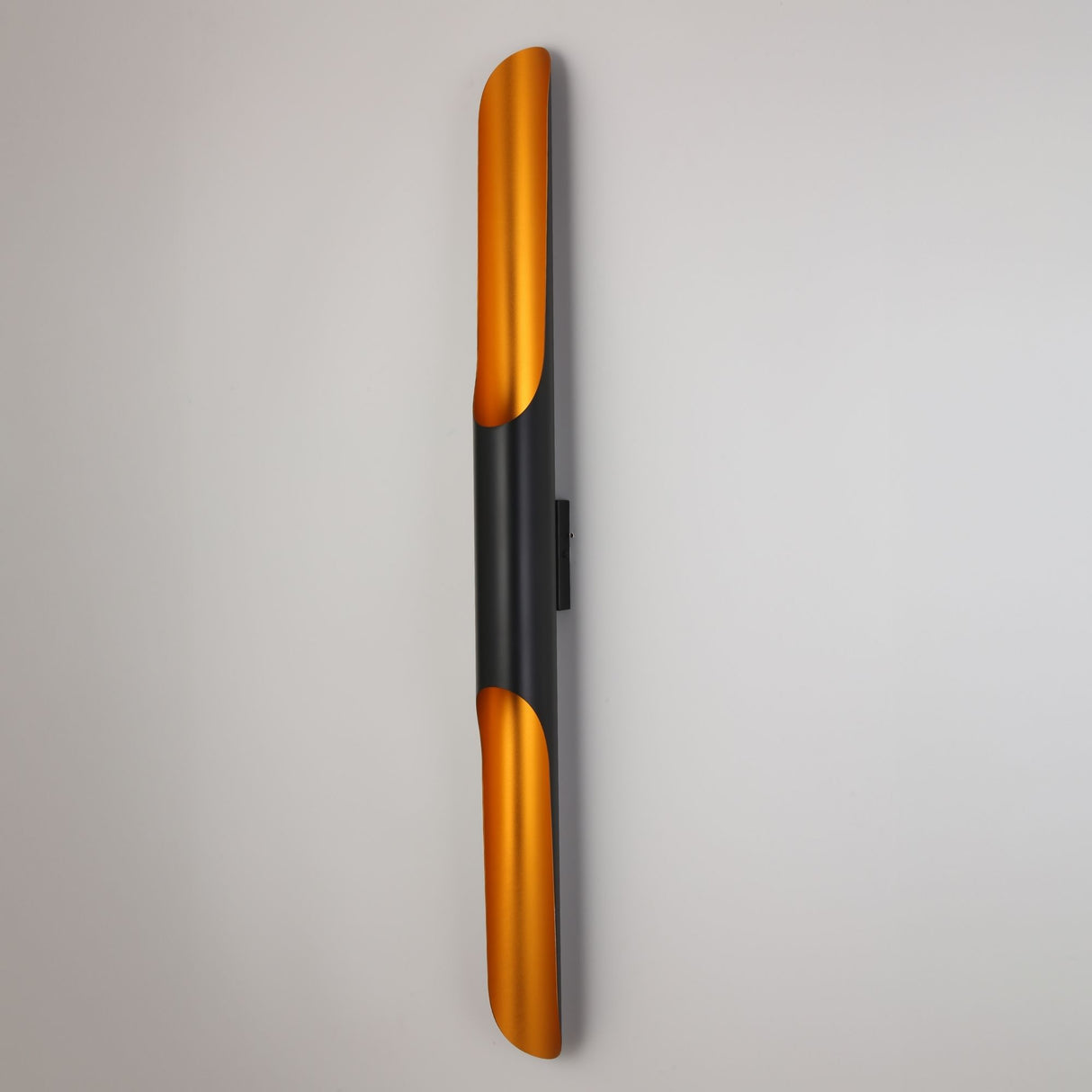 Niori Stealth 2 Light Wall Light mounted vertically, showing the slim matt black tubular body with curved brushed brass scoops at each end.